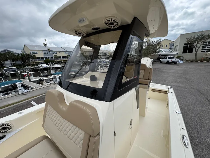 Slide: The Image of 2025 Scout 261 XSS boat with beige seating and modern console at a marina. - 15