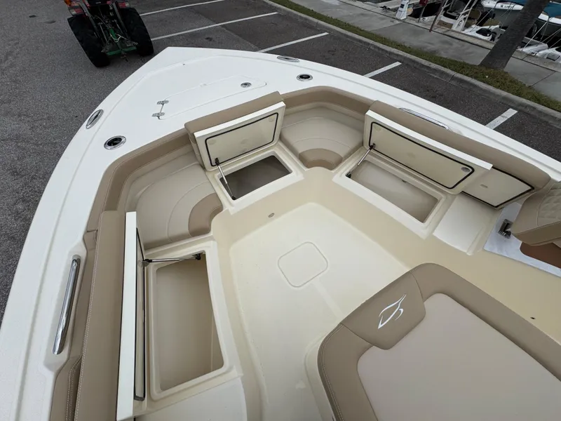 Slide: The Image of 2025 Scout 261 XSS boat interior with open storage compartments and beige seating. - 18