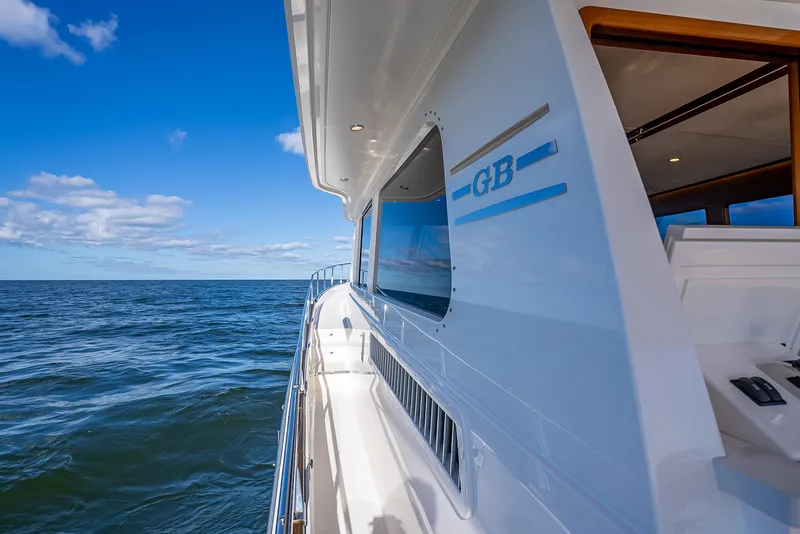 Slide: The Image of 2026 Grand Banks GB 54 yacht cruising on open sea under clear blue sky. - 28