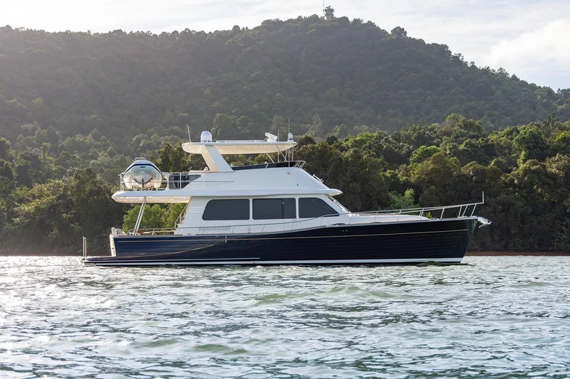 Slide: The Image of 2026 Grand Banks GB 54 yacht cruising near lush green hills. - 3