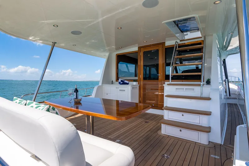 Slide: The Image of 2026 Grand Banks GB 54 yacht deck with wooden table, stairs, and ocean view. - 31