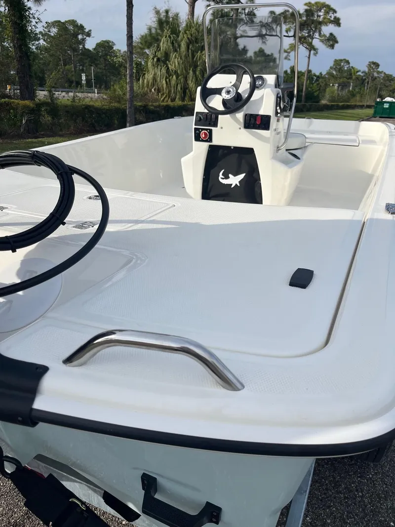 Slide: The Image of 2025 Mako Pro Skiff 17 CC boat, white interior, steering console, outdoor setting. - 2
