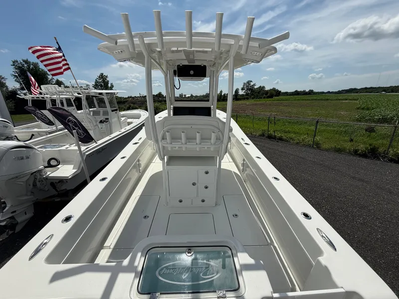 Slide: The Image of 2026 Pair Customs 28 boat with T-top, docked near grassy field under blue sky. - 6