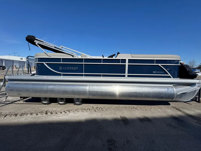 Slide: The Image of 2025 Xperience 2286 SBX pontoon boat with blue and silver design, docked outdoors. - 1