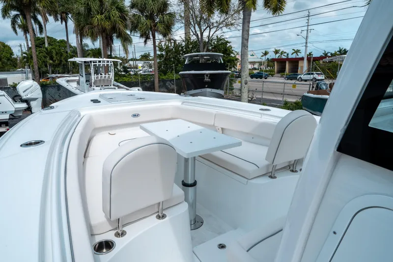 Slide: The Image of 2025 Sea Hunt Ultra 275 SE boat with white seating and table, surrounded by palm trees. - 34