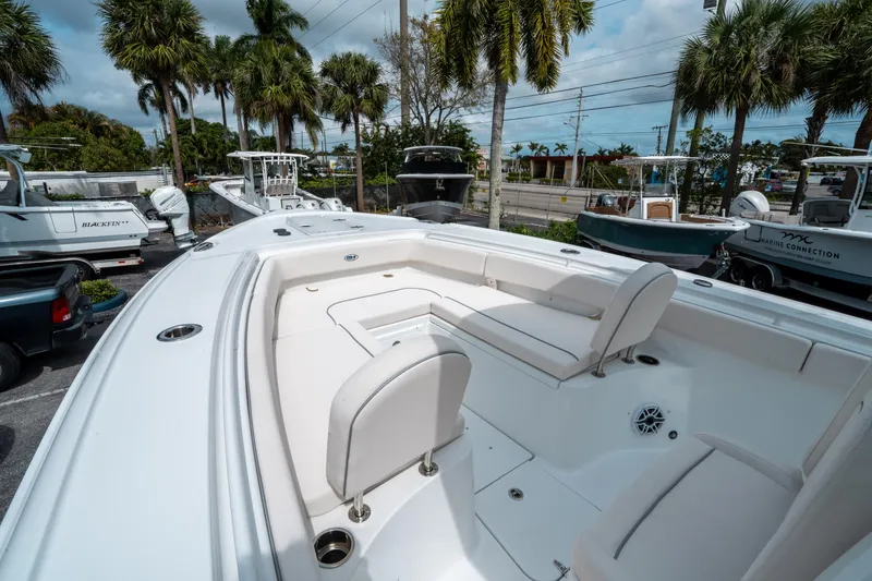 Slide: The Image of 2025 Sea Hunt Ultra 275 SE boat with spacious seating, parked under palm trees. - 31
