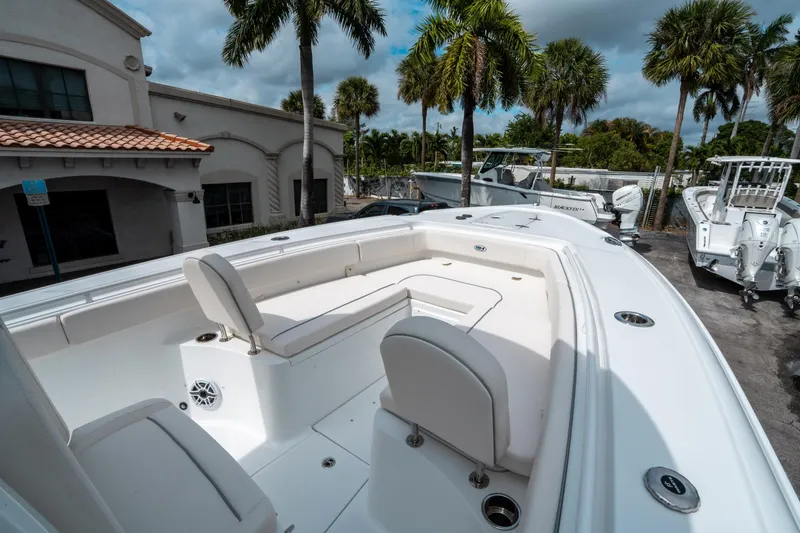 Slide: The Image of 2025 Sea Hunt Ultra 275 SE boat with spacious seating, parked outdoors under palm trees. - 32