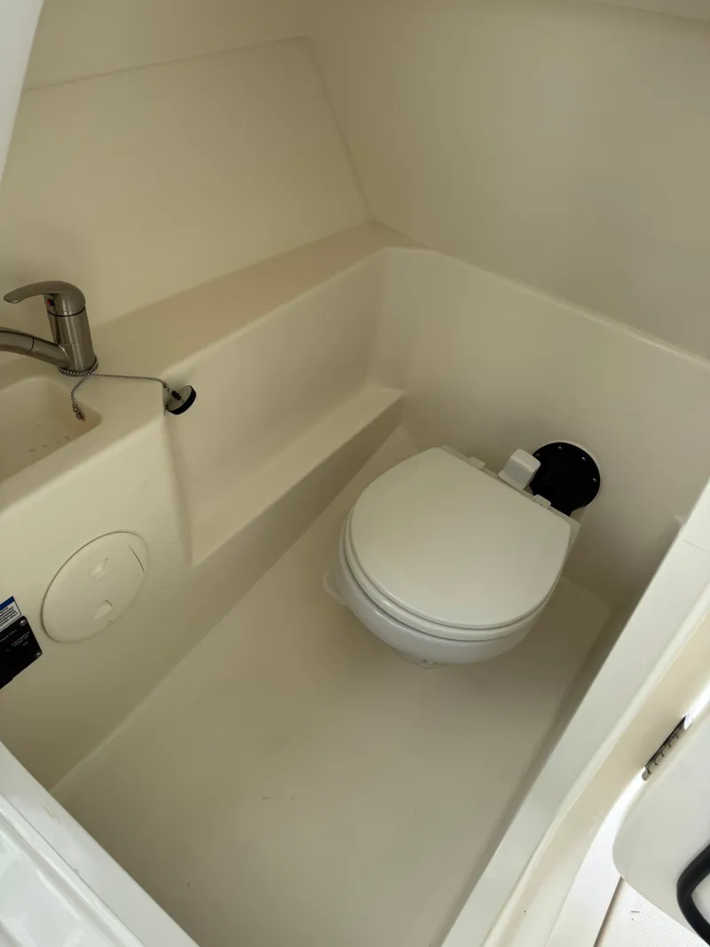 Slide: The Image of 2022 Boston Whaler 240 Vantage boat interior with compact marine toilet and sink. - 16