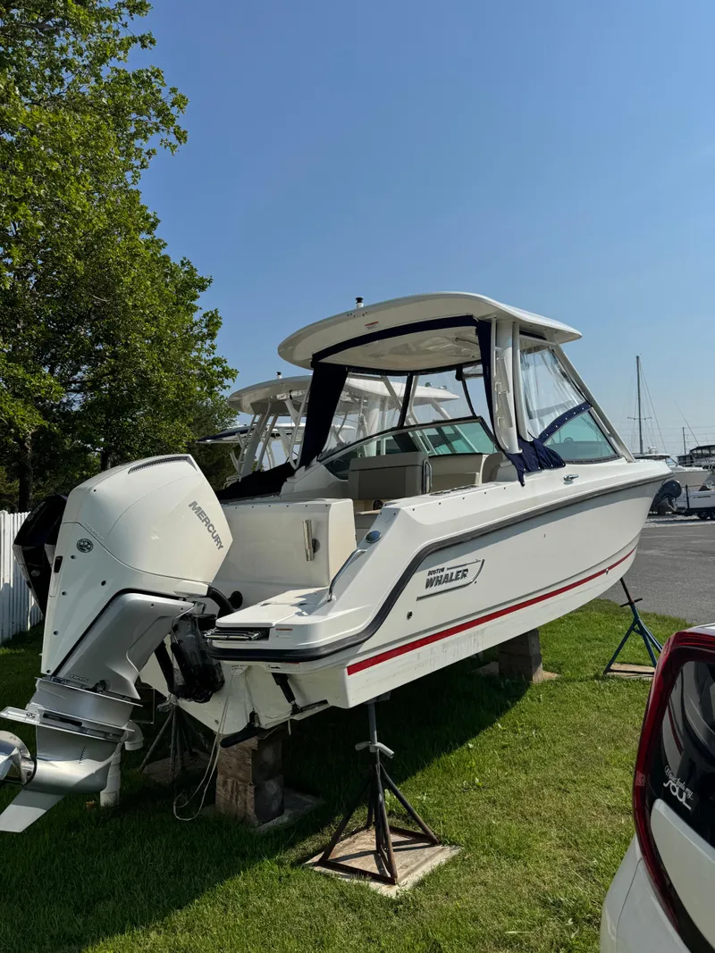 Slide: The Image of 2022 Boston Whaler 240 Vantage boat on grass, with outboard motor and canopy. - 2