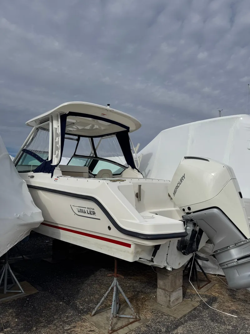 Slide: The Image of 2022 Boston Whaler 240 Vantage boat with Mercury outboard engine, stored on stands. - 3