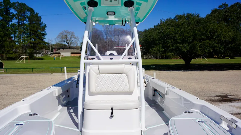 Slide: The Image of 2022 Blue Wave 2600 PureBay boat interior with seating and console, parked outdoors. - 10