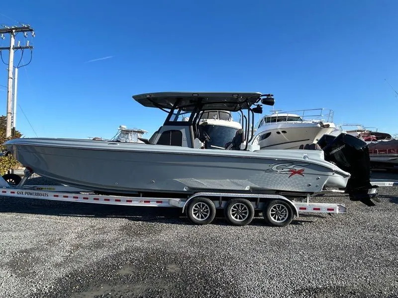 Slide: The Image of 2024 Glasstream 32 GSX boat on trailer, parked outdoors under clear blue sky. - 2