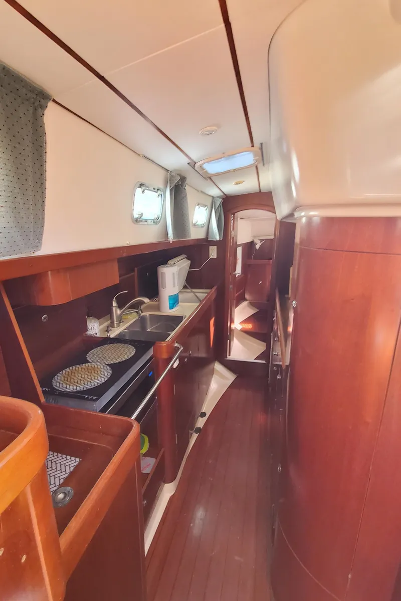 Slide: The Image of Interior of 1999 Beneteau Oceanis 44 CC sailboat with wooden cabinetry and compact kitchen. - 35