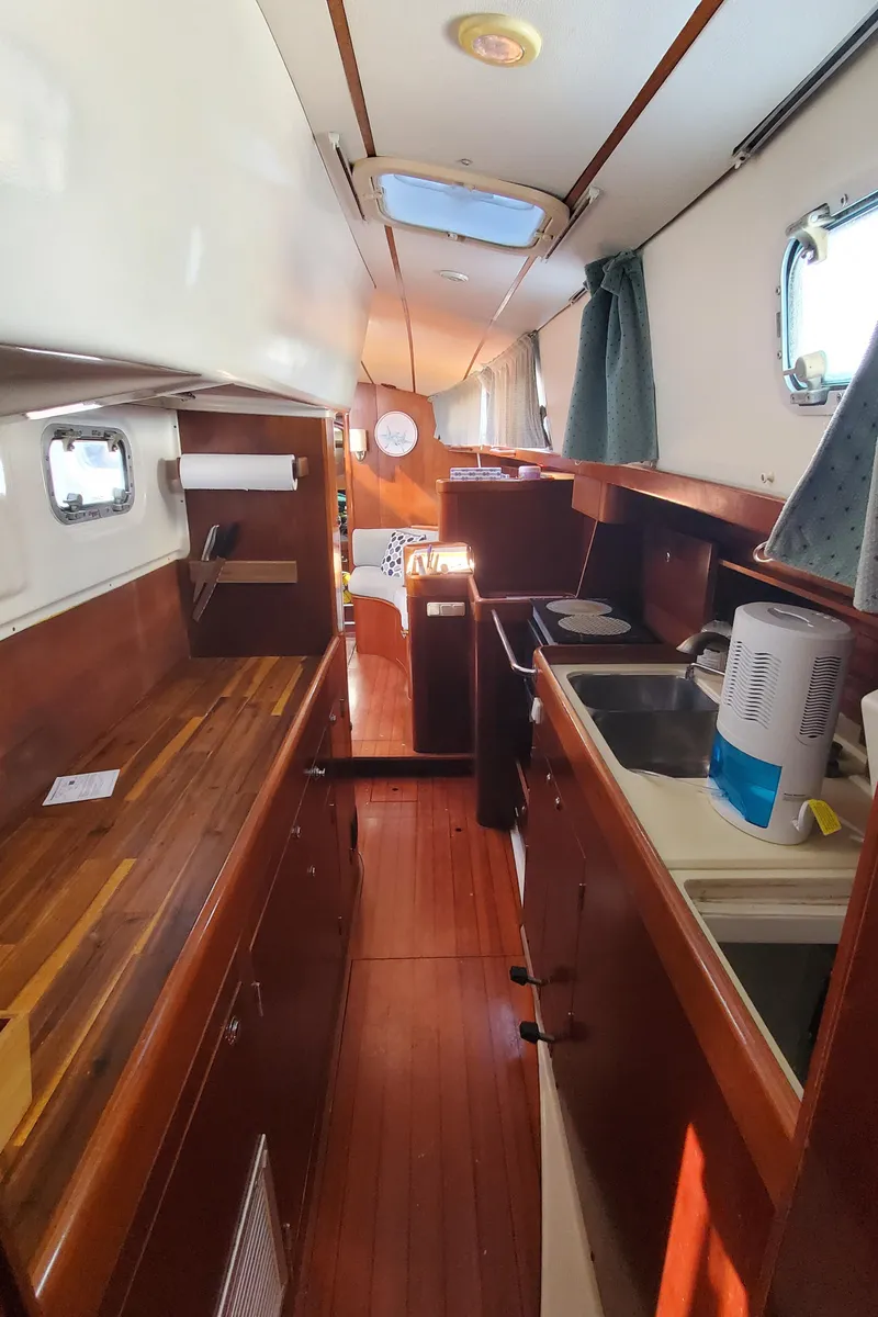Slide: The Image of 1999 Beneteau Oceanis 44 CC interior with wooden cabinetry and galley kitchen. - 36