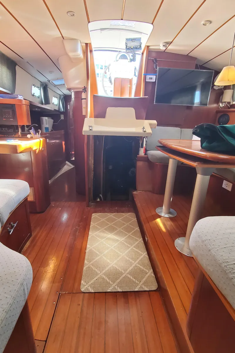 Slide: The Image of Interior of 1999 Beneteau Oceanis 44 CC sailboat with wooden flooring and cozy seating area. - 43
