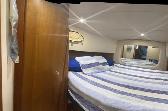 Slide: The Image of 1998 Silverton 372 Motor Yacht bedroom with striped bedding and wooden accents. - 33