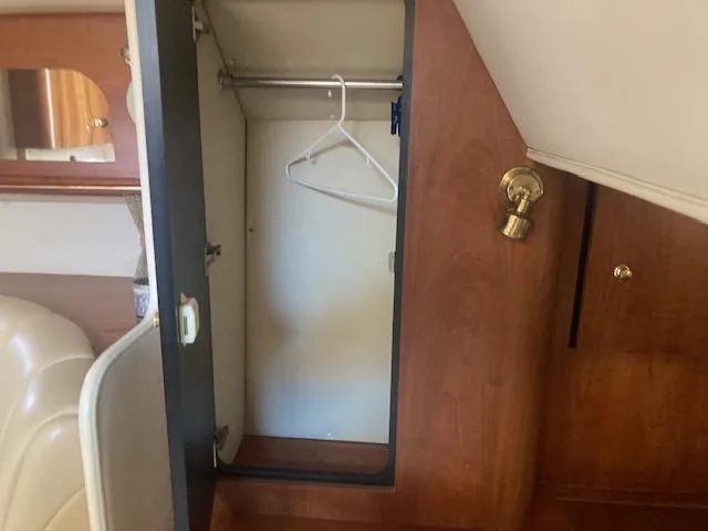 Slide: The Image of Open closet inside 2000 Cruisers Yachts 3575 Express, featuring wooden interior and hangers. - 14