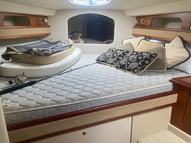 Slide: The Image of 2000 Cruisers Yachts 3575 Express cabin with bed, pillows, and porthole window. - 17