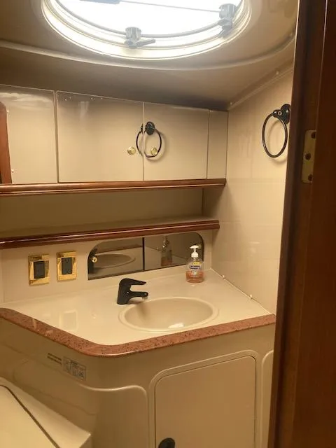 Slide: The Image of 2000 Cruisers Yachts 3575 Express bathroom with sink, mirror, and porthole window. - 18