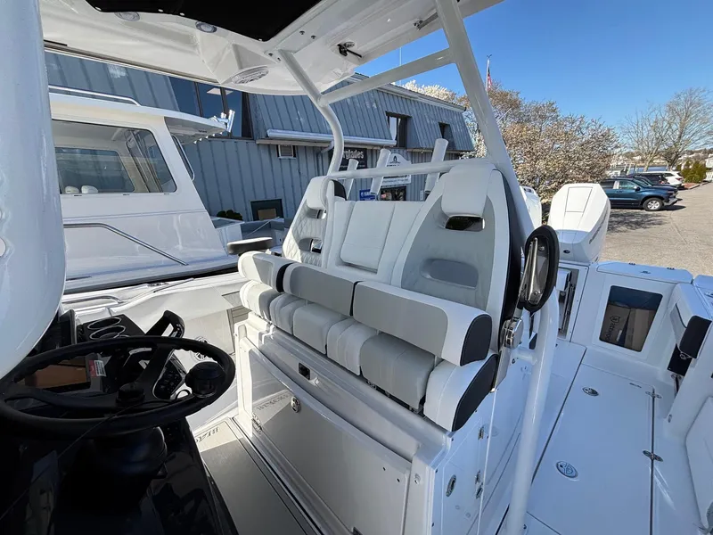 Slide: The Image of 2025 Blackfin 332 CC boat interior with modern seating and steering wheel, docked outdoors. - 10