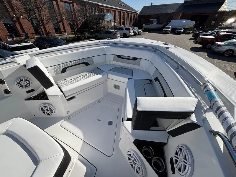 Slide: The Image of 2025 Blackfin 332 CC boat interior with white seating and speakers, docked outdoors. - 13