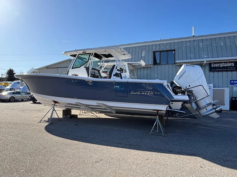 Slide: The Image of 2025 Blackfin 332 CC boat displayed outdoors on stands. - 2
