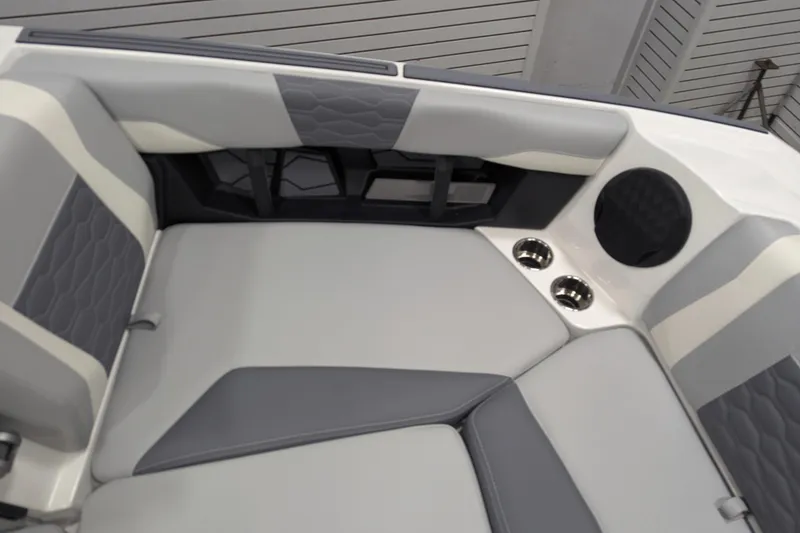 Slide: The Image of 2025 Malibu Wakesetter 24 MXZ interior with gray and white seating, cup holders, and speaker. - 11