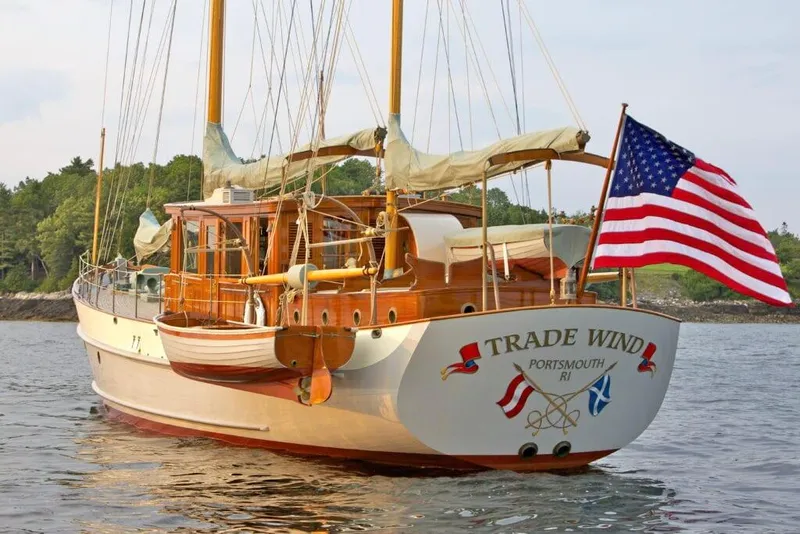 The Image of Classic 1938 Alden yacht "Trade Wind" with American flag, sailing near lush shoreline. - 0