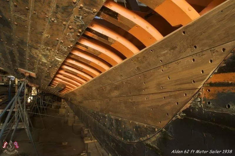 Slide: The Image of Alden 62 ft motor sailer under restoration, showcasing wooden hull and framework, 1938 design. - 11