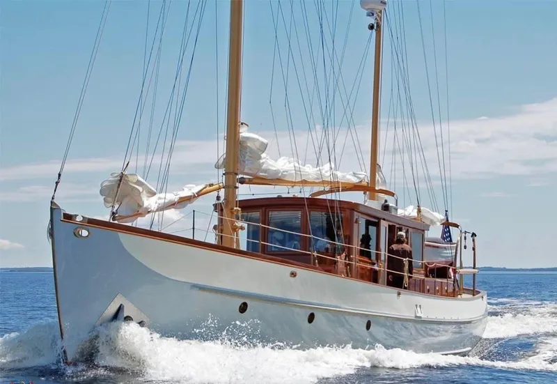 Slide: The Image of Classic 1938 Alden yacht sailing on open water, featuring elegant wooden design and white sails. - 2