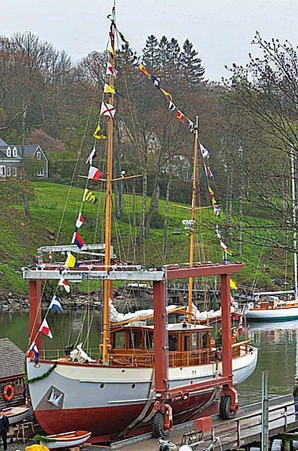 Slide: The Image of Vintage 1938 Alden sailboat, custom design, docked with colorful flags, surrounded by lush greenery. - 20