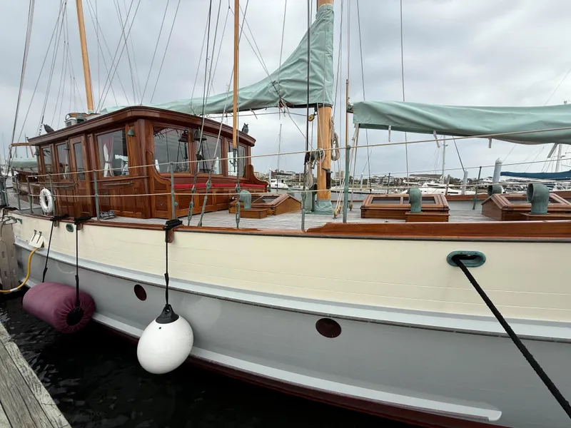 Slide: The Image of Classic 1938 Alden yacht with wooden cabin and green sails, docked at a marina. - 22