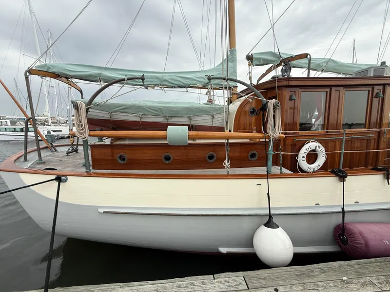 Slide: The Image of Classic 1938 Alden yacht with wooden cabin, docked at marina, featuring green canopy and lifebuoy. - 24