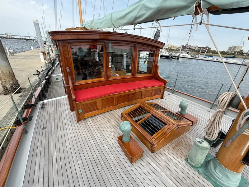 Slide: The Image of Classic 1938 Alden yacht deck with wooden cabin, red seating, and marina view. - 31