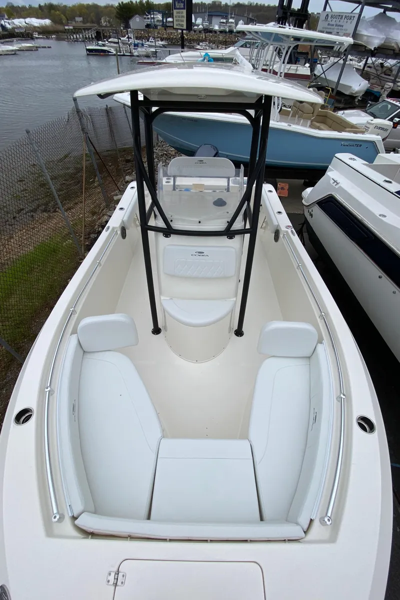 Slide: The Image of 2025 Cobia 220 boat with spacious seating and T-top, docked near other boats. - 10