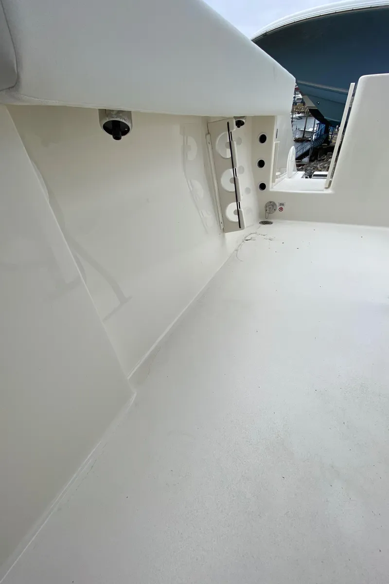 Slide: The Image of 2025 Cobia 220 boat interior, showcasing sleek white deck and storage compartments. - 13