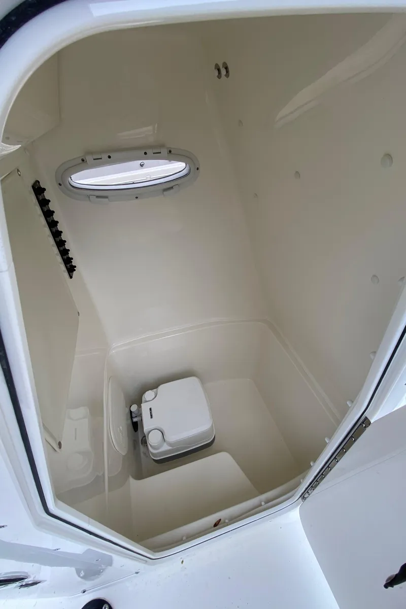 Slide: The Image of 2025 Cobia 220 boat interior with compact marine toilet and small window. - 17