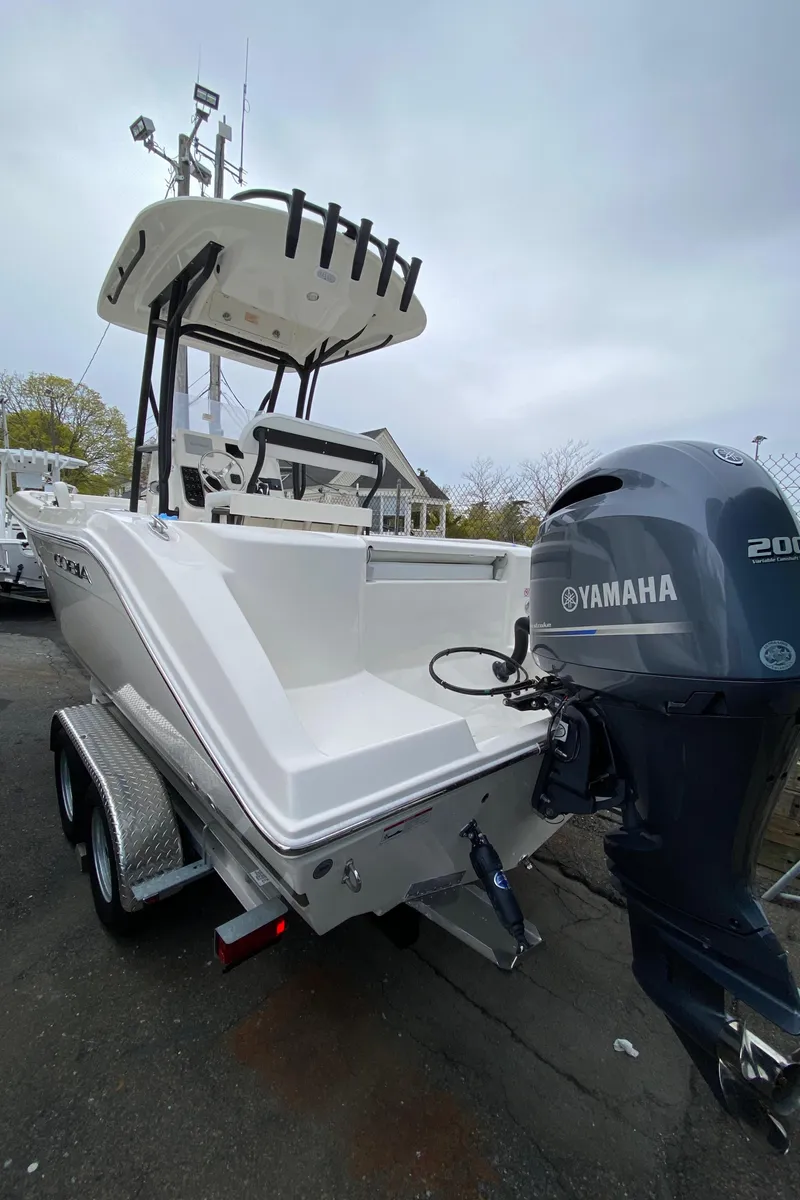 Slide: The Image of 2025 Cobia 220 boat with Yamaha 200 engine on trailer, outdoor setting. - 2