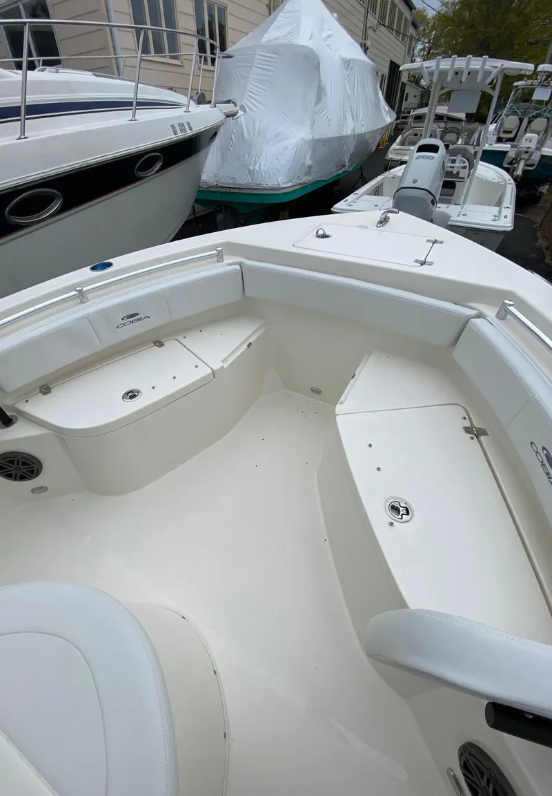 Slide: The Image of 2025 Cobia 220 boat interior, featuring spacious seating and sleek design in a marina setting. - 7