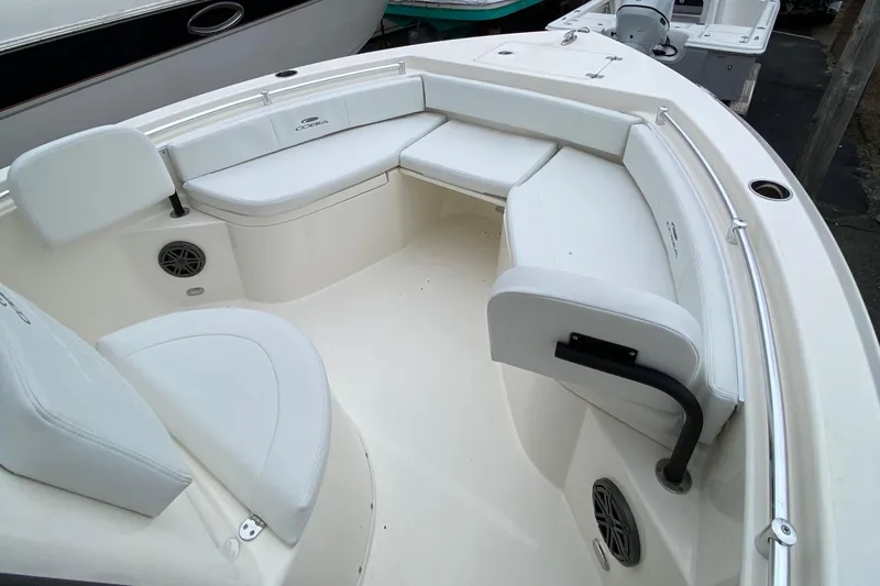 Slide: The Image of 2025 Cobia 220 boat interior with white cushioned seating and built-in speakers. - 8