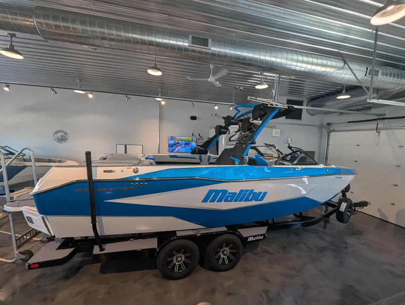 Slide: The Image of 2025 Malibu Wakesetter 25 LSV boat in showroom, blue and white design. - 1