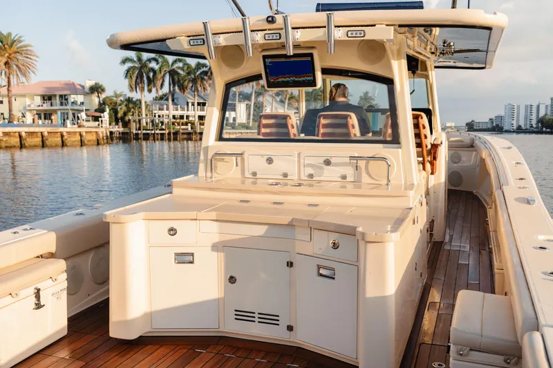 Slide: The Image of 2022 HCB 53 Sueños boat with luxurious deck and seating, docked near waterfront homes. - 16