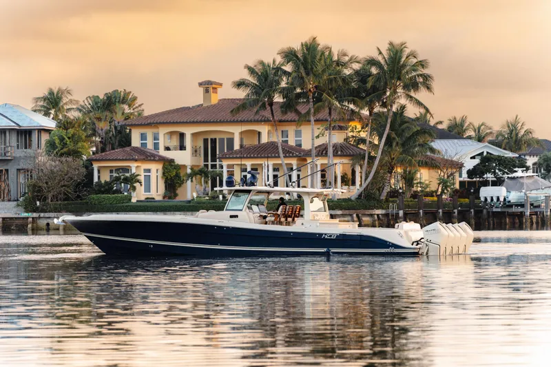 Slide: The Image of 2022 HCB 53 Sueños boat on calm water, luxury waterfront homes in background. - 5