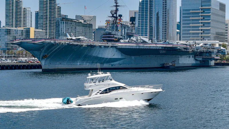 Slide: The Image of 2008 Sea Ray 58 Sedan Bridge yacht cruising near a large battleship in an urban harbor. - 3