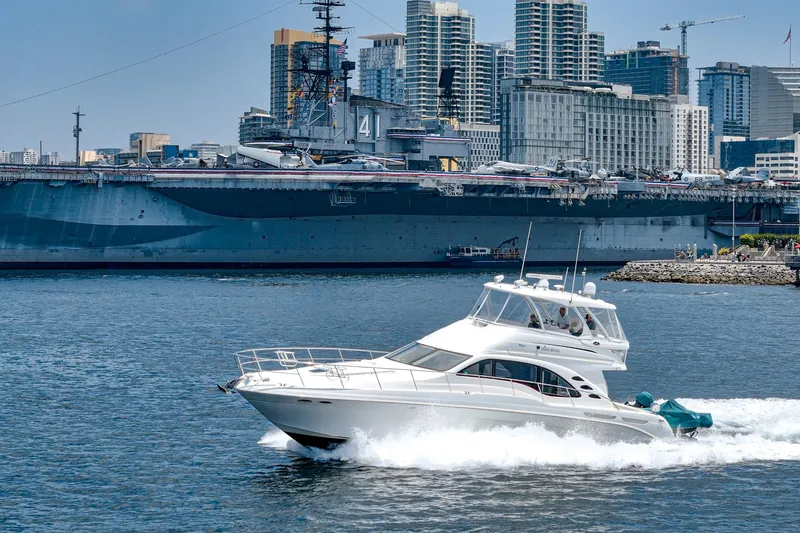 Slide: The Image of 2008 Sea Ray 58 Sedan Bridge yacht cruising near a large battleship and city skyline. - 6