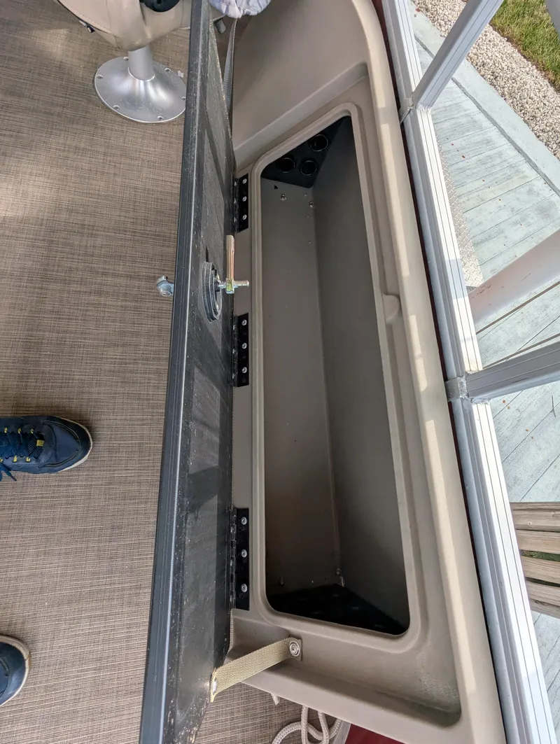 Slide: The Image of 2021 Sun Tracker Fishin' Barge 22 DLX storage compartment, open lid, beige interior. - 10