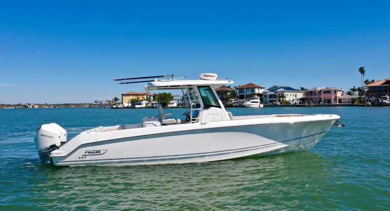 The Image of 2022 Boston Whaler 330 Outrage boat on calm water, with coastal homes in the background. - 0