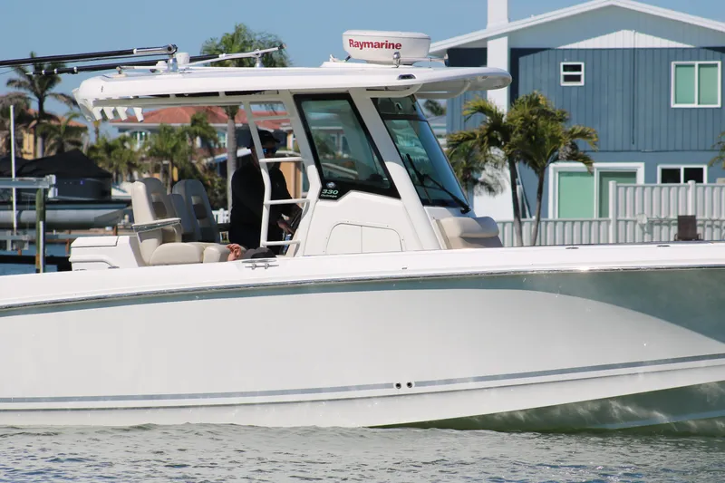 Slide: The Image of 2022 Boston Whaler 330 Outrage boat cruising near waterfront homes. - 10