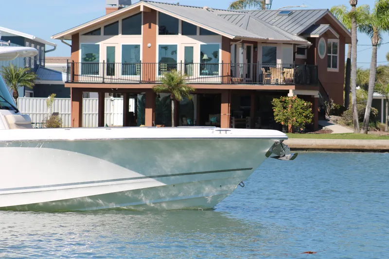 Slide: The Image of 2022 Boston Whaler 330 Outrage boat near waterfront house with palm trees. - 11