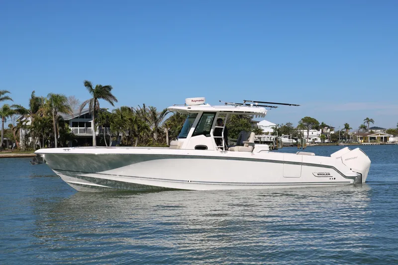 Slide: The Image of 2022 Boston Whaler 330 Outrage boat on calm water, surrounded by palm trees. - 14